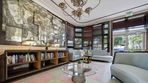 Eine Lobby mit einem Glastisch, Bücherregalen, einer Couch und einem großen abstrakten Gemälde an der Wand.