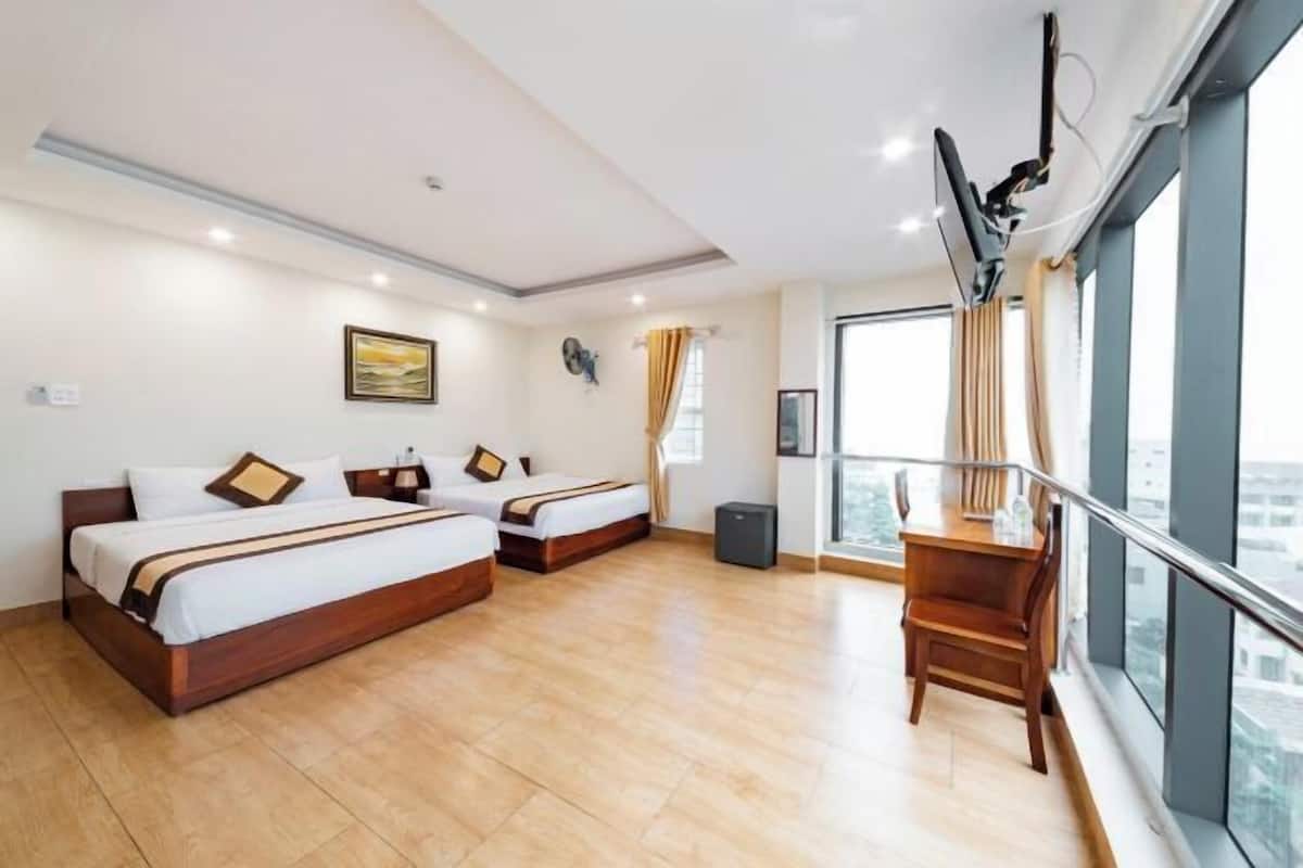 Une chambre d’hôtel avec deux lits, un bureau, une chaise, une télévision et une fenêtre donnant sur la ville.