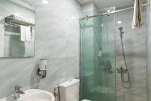 Ein modernes Badezimmer mit einer Duschkabine, einem Waschbecken mit Spiegel und einer Toilette.