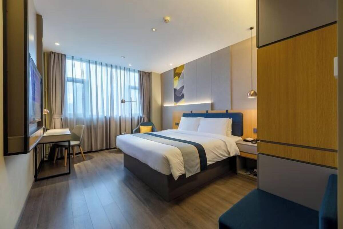 A modern hotel room with a large bed, a desk, and a chair.