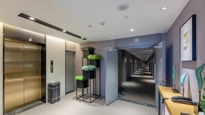 A modern hotel lobby with a reception desk, an elevator, and a hallway leading to other areas. - Homeinn Selected Hotel (Zhengzhou Huayuan Road Grand Emporium) (Zhengzhou)
