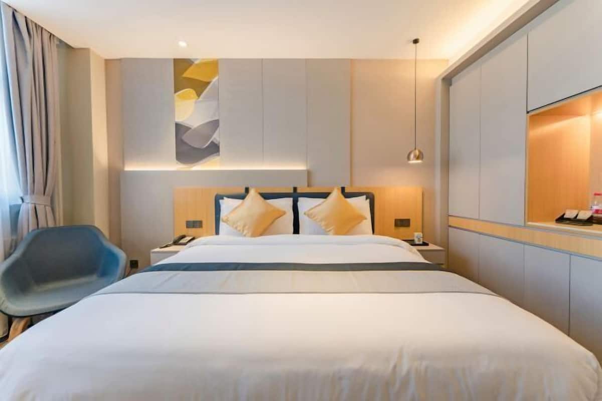 A modern hotel room with a large bed, a desk, and a chair.