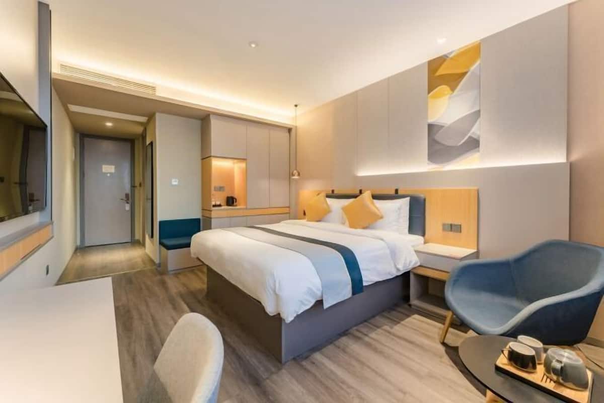 A modern hotel room with a large bed, bedside tables, a desk, and a chair.
