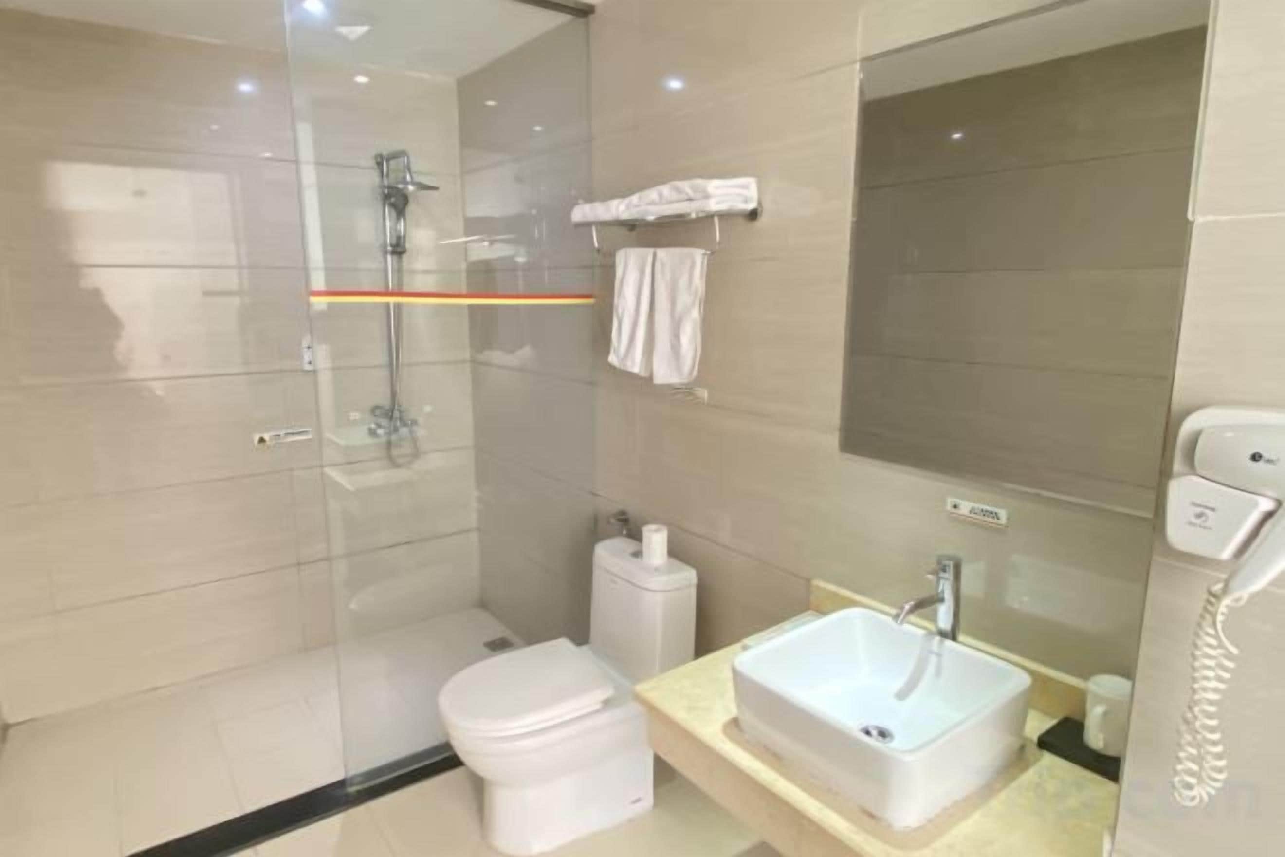 Une salle de bain moderne avec une douche à parois de verre, des toilettes, un lavabo et un miroir.