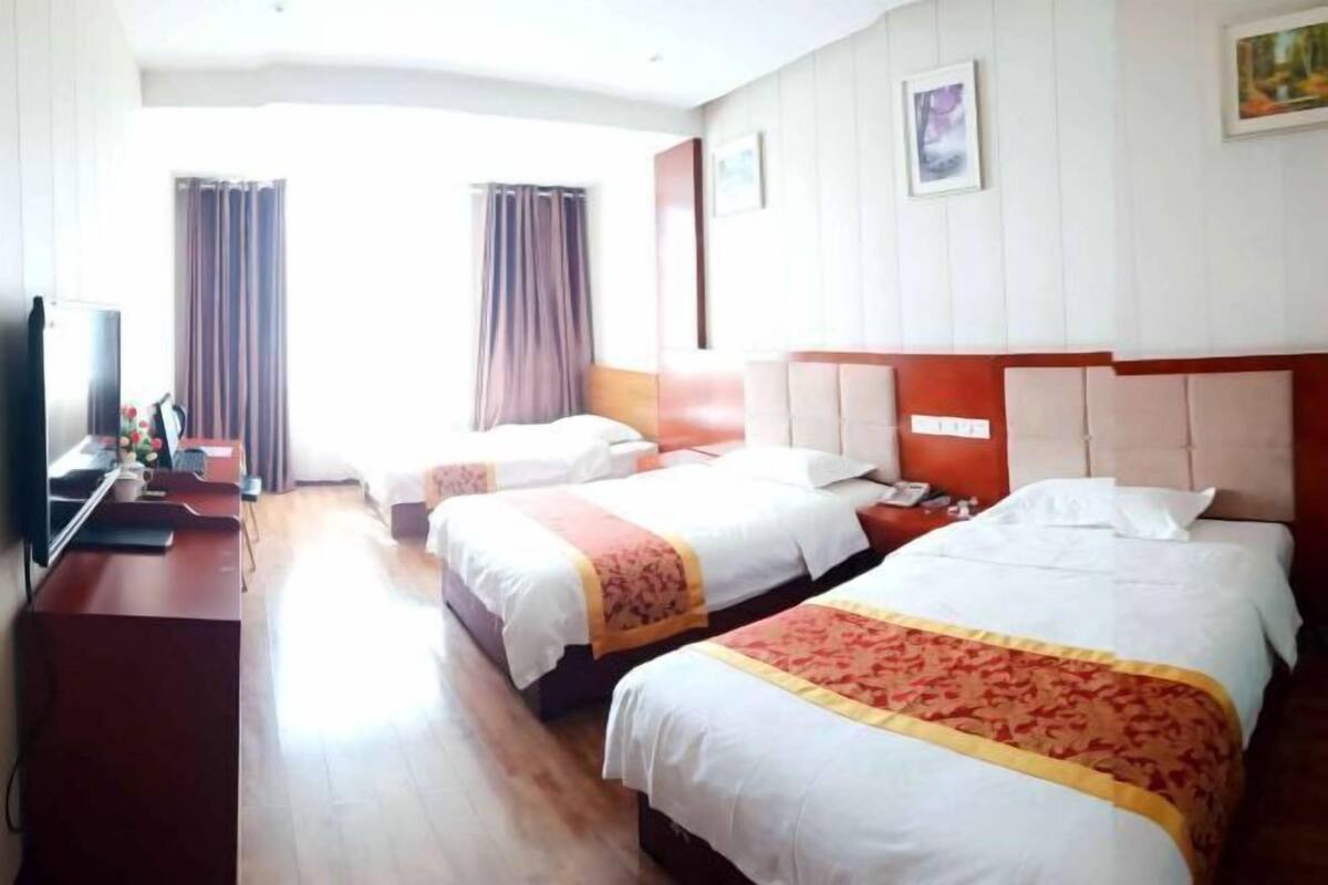 Hotellihuone, jossa on kaksi sänkyä, työpöytä ja televisio.