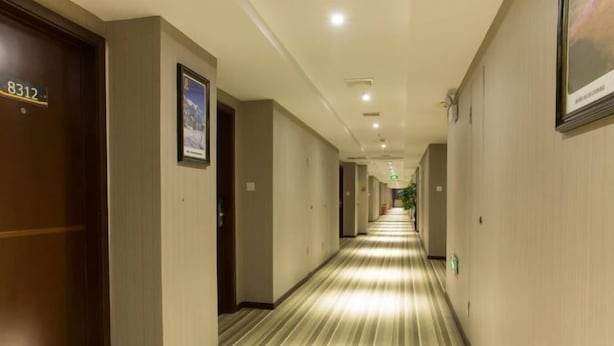 A hotel corridor with wooden doors, beige walls, and a striped carpet. - Yuanke Hotel (Chibi)