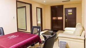 A hotel room with a dining table, two chairs, a sofa, and a trash bin. - Yuanke Hotel (Chibi)