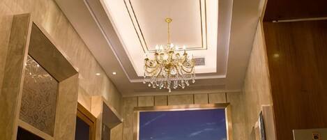 Un hall d’hôtel agrémenté d’un lustre, d’une grande fenêtre offrant une vue panoramique et d’un tableau encadré accroché au mur.