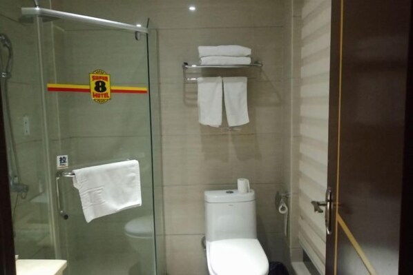 A bathroom with a glass shower enclosure, a toilet, a towel rack, and a sign indicating the hotel name. - Yuanke Hotel (Chibi)