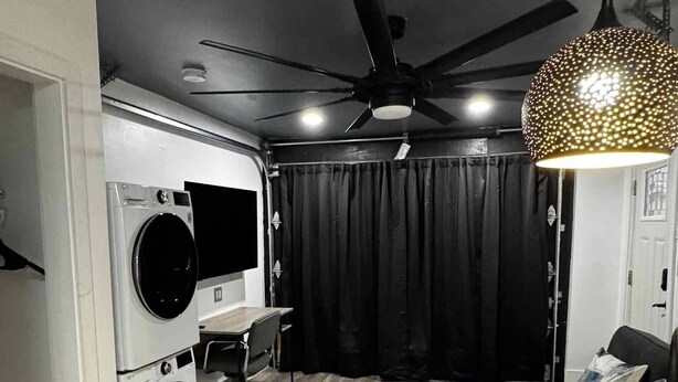 Un espacio habitable funcional con lavadora, escritorio, ventilador de techo y comedor.