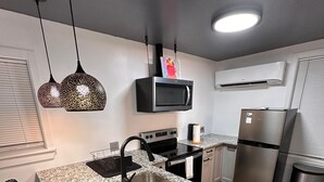Una cocina moderna con encimeras de granito, un lavamanos de acero inoxidable, horno empotrado, microondas y refrigerador.