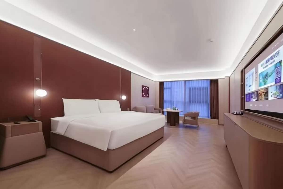 A modern hotel room with a large bed, bedside tables, a desk, and a TV.