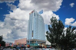 Un hotel alto con diseño moderno, rodeado de otros edificios y un cielo despejado.