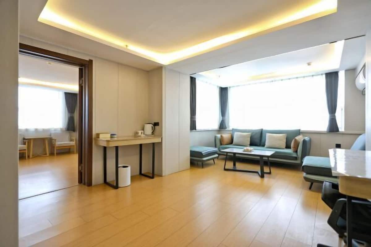 A modern living room with a sofa, coffee table, and a small kitchen area with a counter and sink.