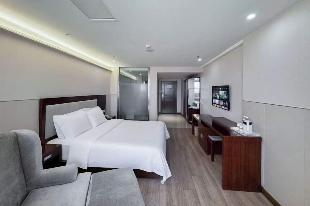 A hotel room with a bed, a desk, a chair, and a television.
