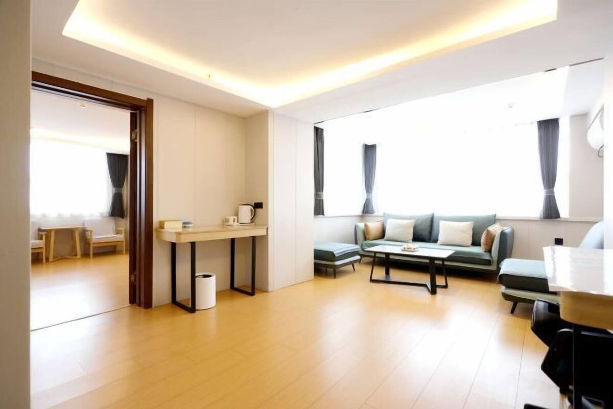 A modern living room with a sofa, coffee table, and a small dining area.