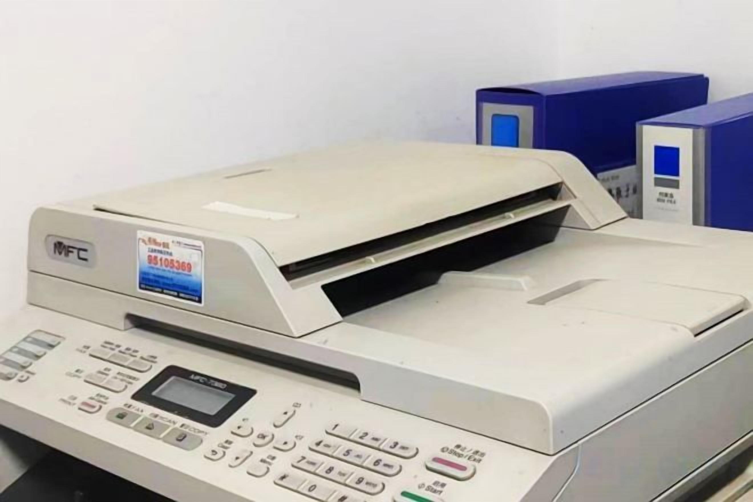 A multifunction printer with a control panel, positioned next to a blue filing cabinet.