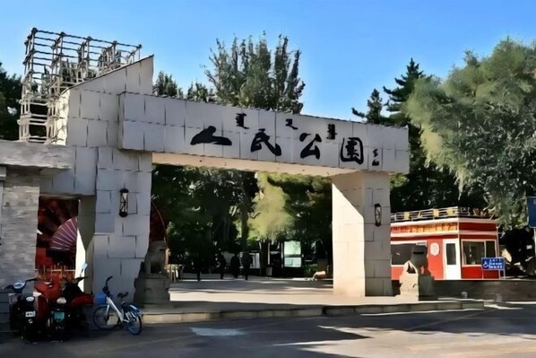 A stone archway with Chinese characters, a red bus, and a bicycle. - Super 8 Hotel (Tongliao Railway Station Jianguo Road) (Tongliao)