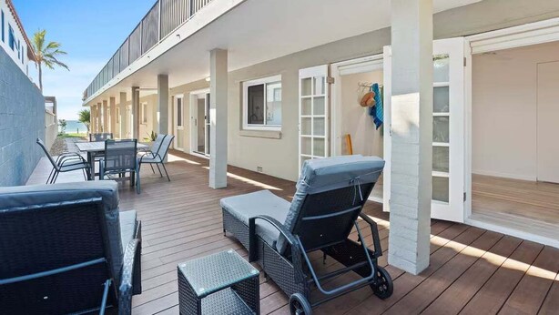 A covered outdoor patio with seating and a view of the ocean.