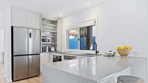 A modern kitchen with a large island, stainless steel appliances, and a view of the outdoors.