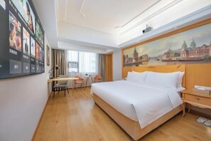 A hotel room with a large bed, a desk with two chairs, a painting on the wall, and a window with curtains. - Vienna International Hotel (Fuzhou)
