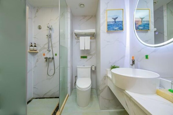 A bathroom with a shower, toilet, sink, and two framed pictures on the wall. - Vienna International Hotel (Fuzhou)