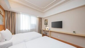 A hotel room with two beds, a desk, a television, and a window with curtains. - Vienna International Hotel (Fuzhou)
