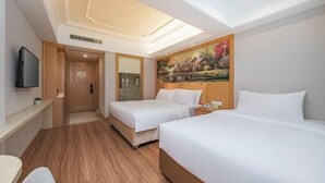A hotel room with two beds, a painting on the wall, a TV mounted on the wall, and a wooden floor. - Vienna International Hotel (Fuzhou)