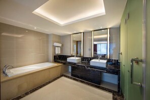 A modern bathroom with a bathtub, two sinks, and a large mirror. - Huacai Hotel (Wuyishan)