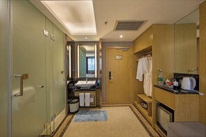 A hotel bathroom with a sink, mirror, towel rack, and a shower area. - Huacai Hotel (Wuyishan)