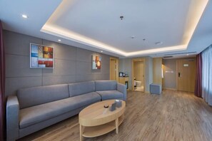 Un vestíbulo de hotel moderno con un sofá gris, una mesa de centro de madera y dos cuadros abstractos en la pared.