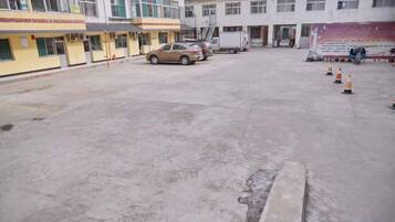 A parking lot with a few cars, a building with multiple windows, and a few traffic cones.