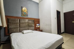 Une chambre d’hôtel avec un grand lit, une tête de lit, une table de chevet, une œuvre d’art accrochée au mur et une porte.