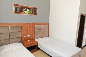 A bedroom with two single beds, a wooden headboard, a nightstand, and a wall-mounted artwork. - Yuanping Xinya Hotel (Yuanping)