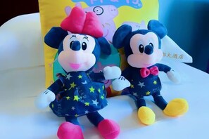Two plush toys on a white surface with a colorful bag in the background.