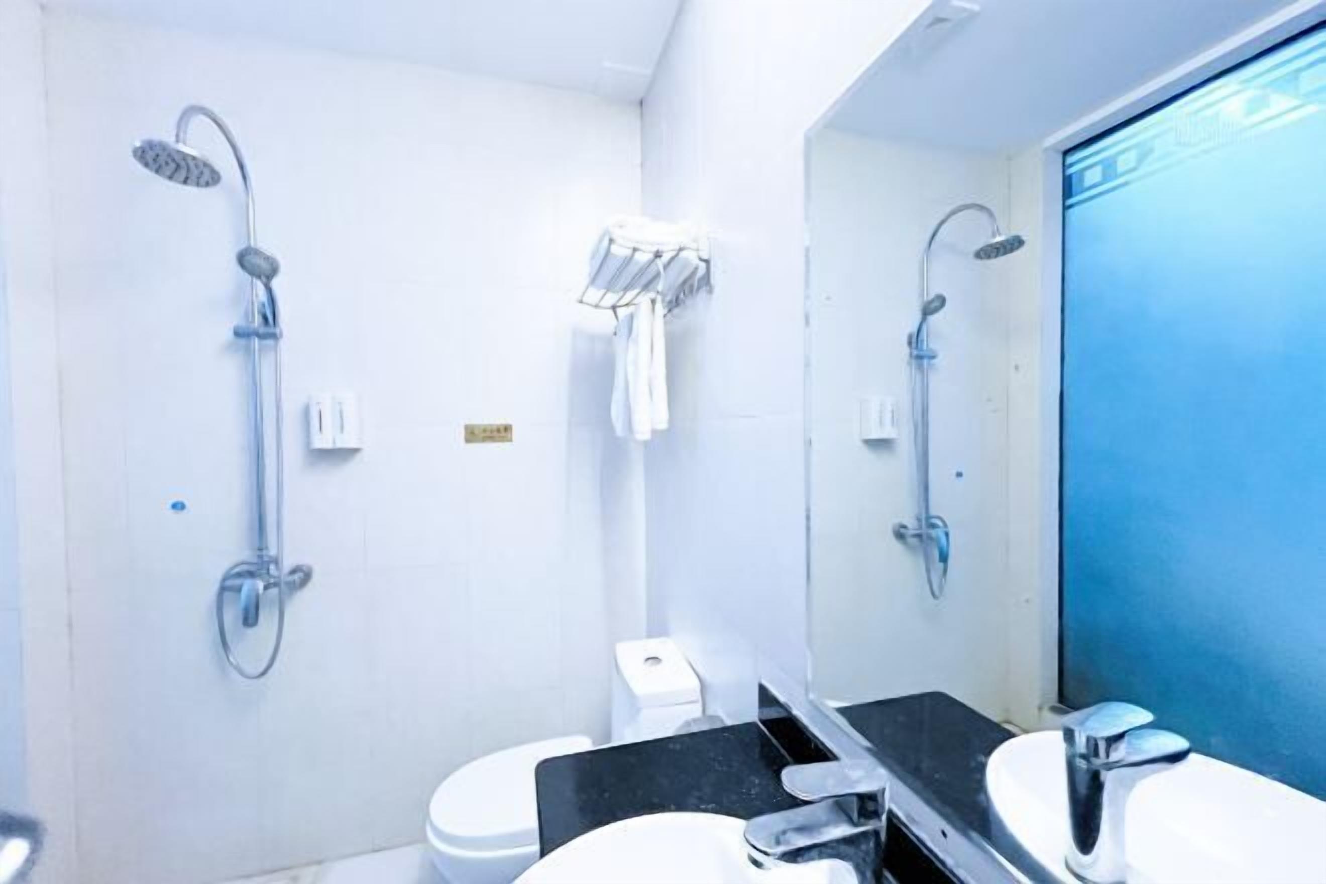 Une salle de bain moderne avec un grand miroir, deux lavabos, une douche et des toilettes.