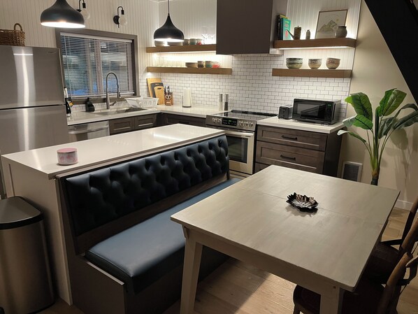 A modern kitchen with a central island, a dining table, and a built-in bench. - Little Giant, concrete built
Serene 2-bedroom house with WiFi in charming Coram (Coram)