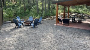 An outdoor seating area with Adirondack chairs and a fire pit, surrounded by a gravel patio and a stone wall. - Little Giant, concrete built
Serene 2-bedroom house with WiFi in charming Coram  (Coram)