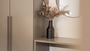 A bedroom with a bed, a wardrobe, a bedside table, a vase with dried flowers, and a round mirror. - Gipfelglück Standard (Kirchberg in Tirol)