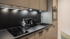 A modern kitchen with a black countertop, built-in appliances, and a stainless steel range hood. - Gipfelglück Standard (Kirchberg in Tirol)