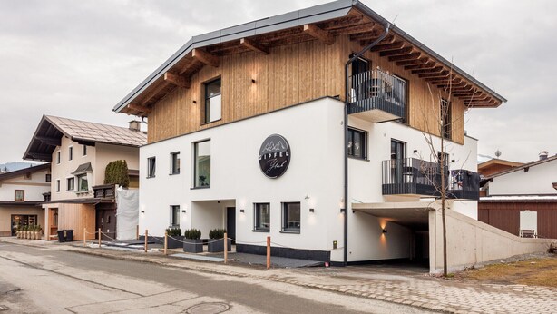 A modern building with a wooden facade, a balcony, and a sign that reads "GIPFEL".