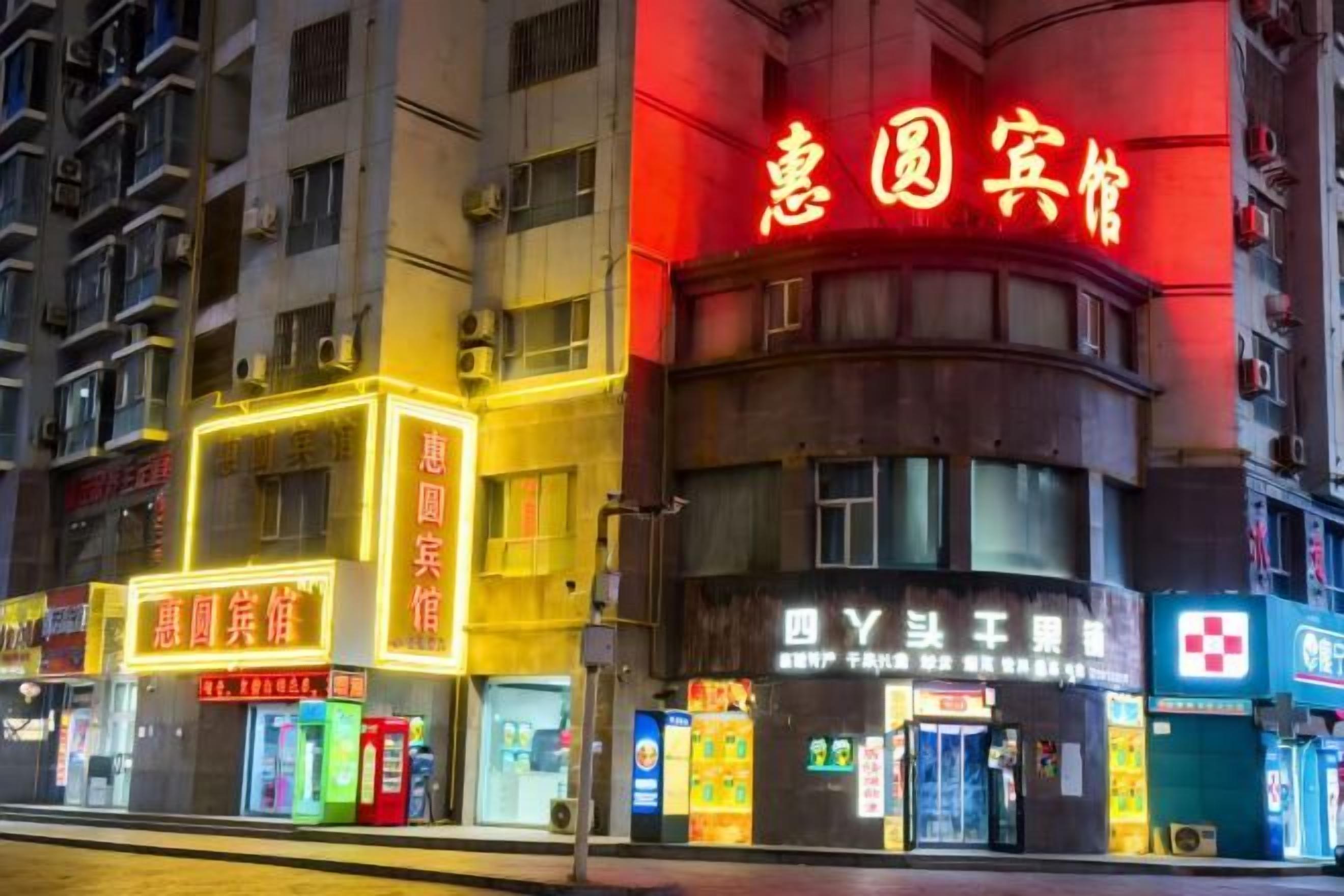 A building with illuminated signage, including a prominent red sign and a yellow sign with Chinese characters.