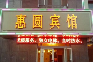 Un letrero de hotel con caracteres chinos y un letrero de neón que indica servicios como 'servicio de alta calidad' y 'agua caliente las 24 horas'.
