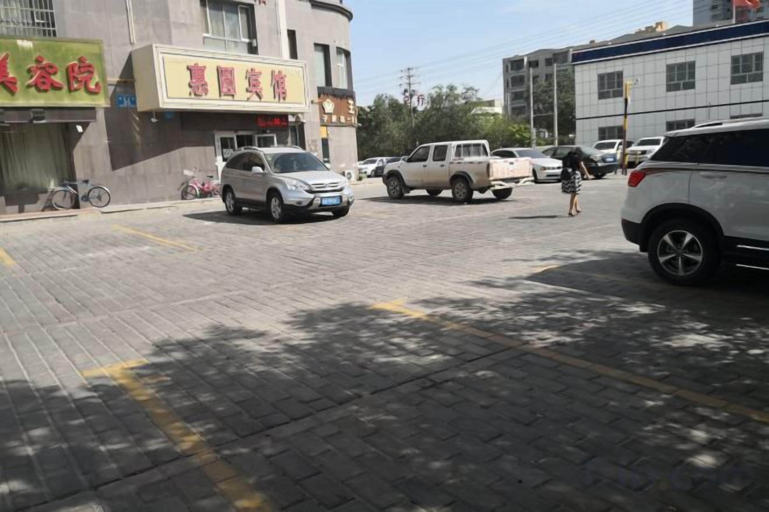 A parking area with vehicles, a building with signage, and a pedestrian walkway.