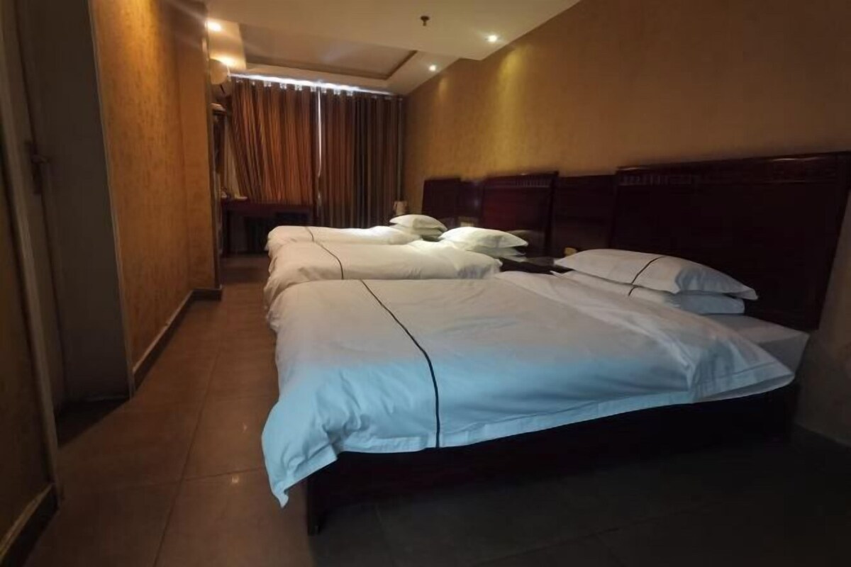 Una habitación de hotel con dos camas, cabeceros de madera y una ventana cubierta por cortinas.