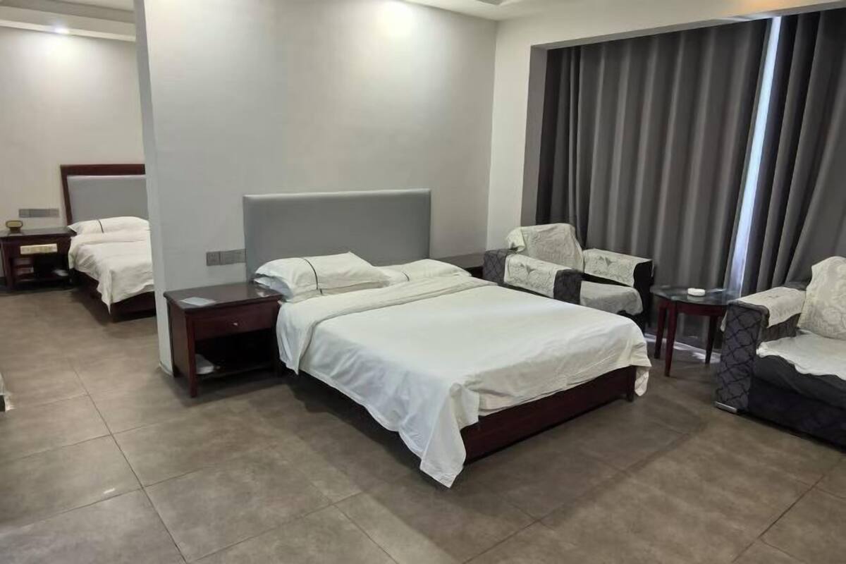 A hotel room with a large bed, a sofa, a small table, and a nightstand.
