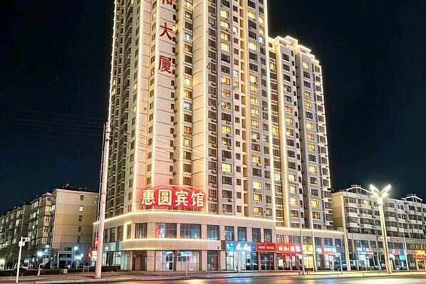 Un edificio alto con varios pisos y una entrada muy iluminada.
