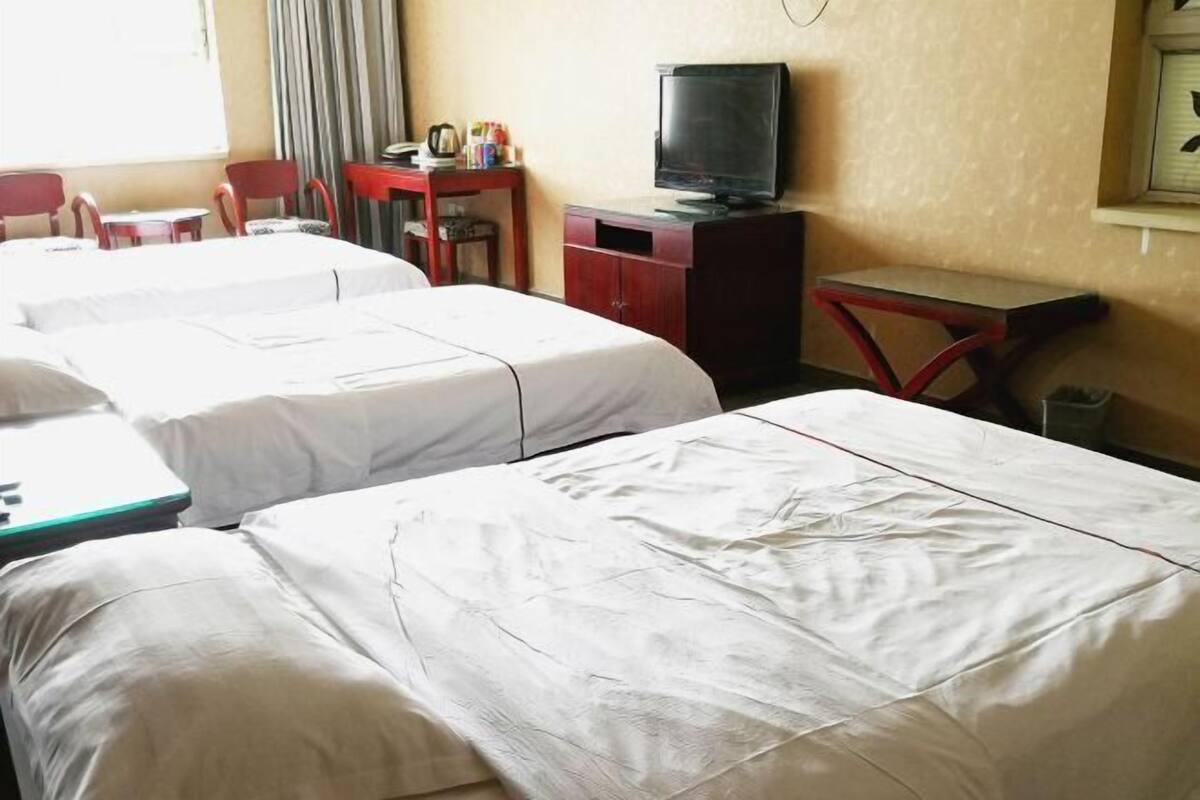 A hotel room with two single beds, a television, a desk with a chair, and a small table.