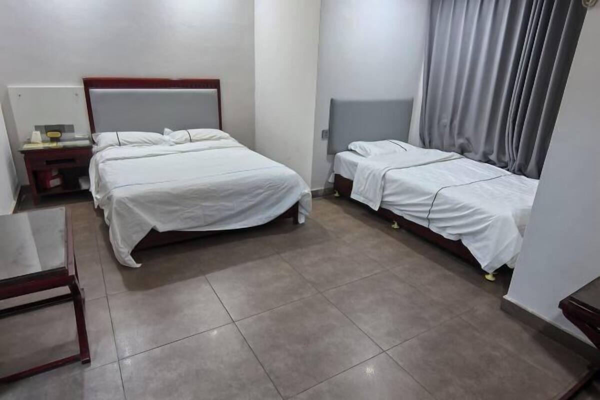 A hotel room with two beds, a small table, and a nightstand.