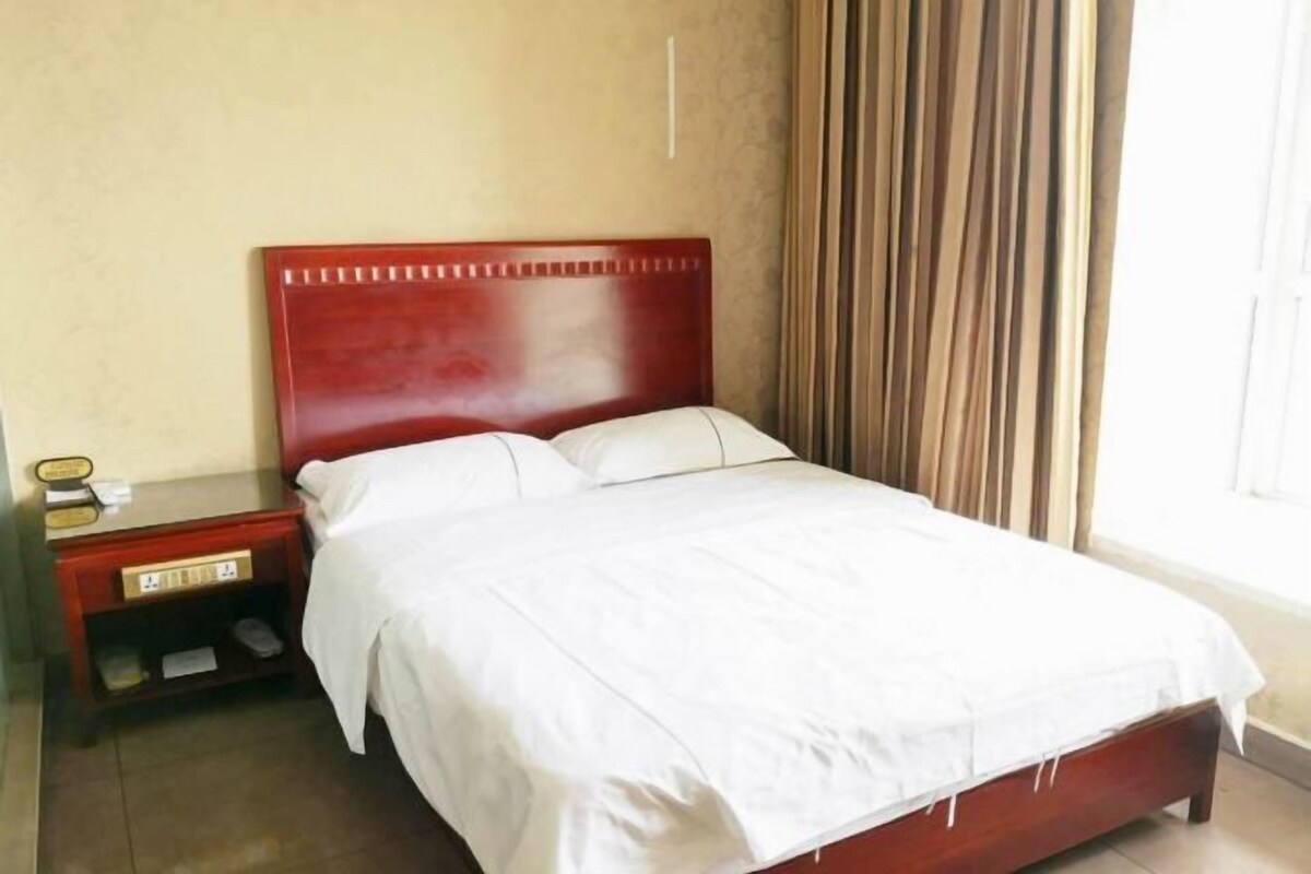 Una cama bien hecha con sábanas blancas en una habitación con cabecera de madera.